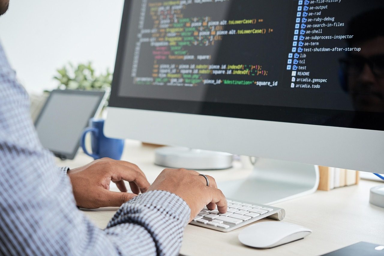 Une personne qui tape sur un ordinateur de bureau affichant du code source